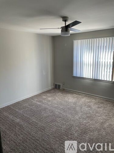 A room with a carpeted floor and a ceiling fan.