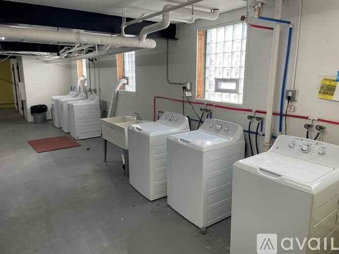 A room with white washing machines and pipes on the wall.
