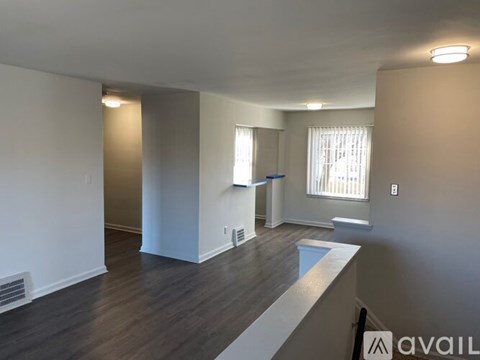 A spacious room with wood flooring and white walls.