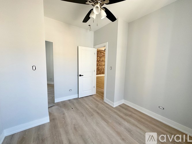 A room with a ceiling fan and a door leading to another room.