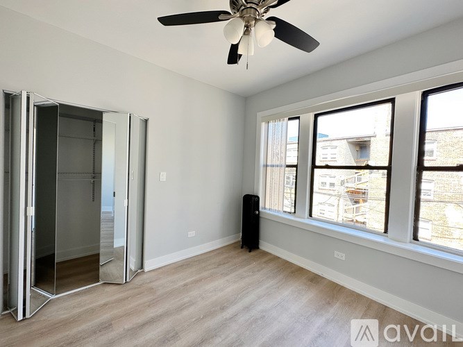 A room with a ceiling fan and a window overlooking a city.