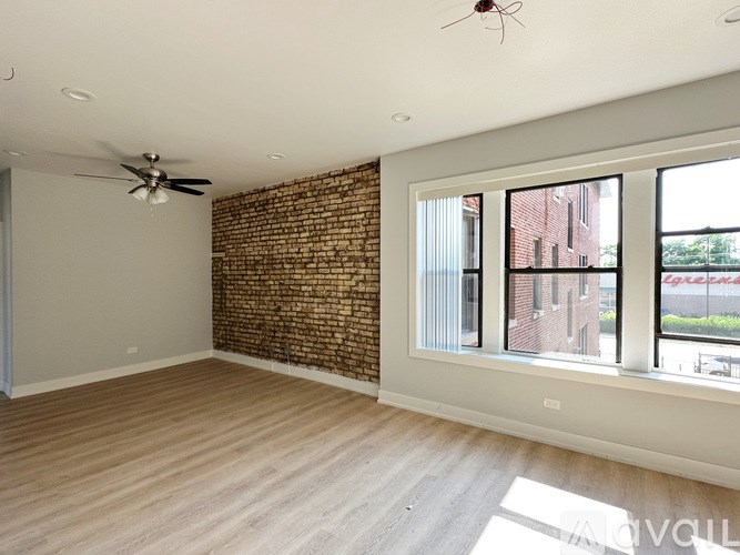 A room with a ceiling fan and a brick wall.