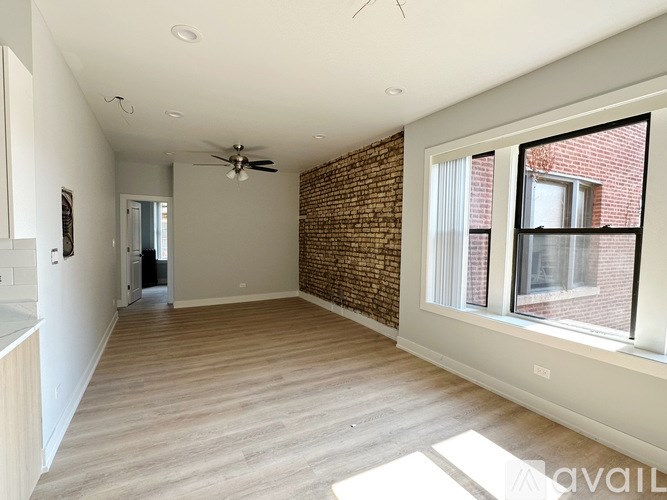 A room with a brick wall and wooden flooring is available for rent.
