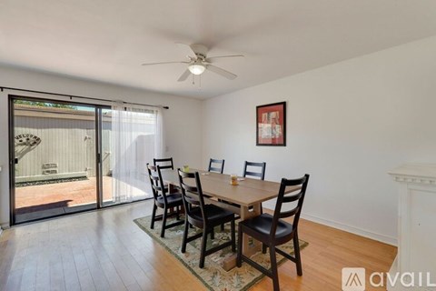 A dining room with a table set for four and a fan on the ceiling.