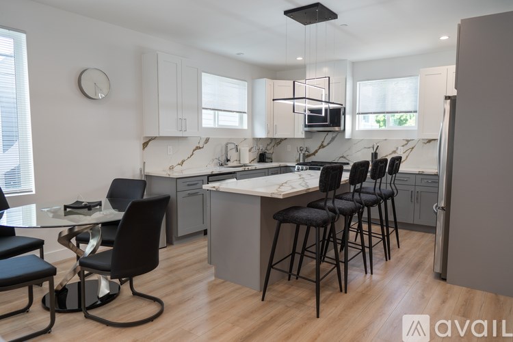 A modern kitchen with black chairs and a marble backsplash.