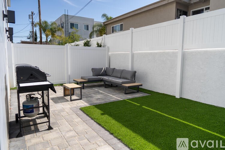 A backyard with a white fence and a green lawn.