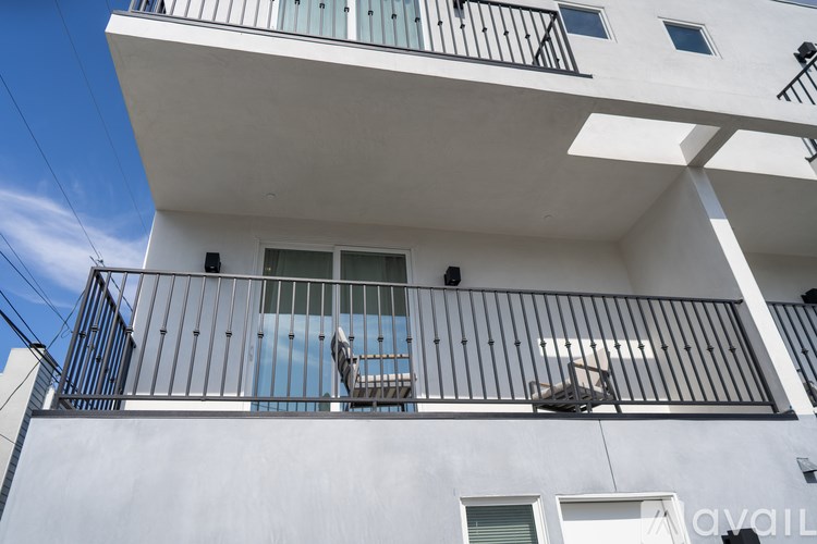 A white building with a balcony and a chair on it.
