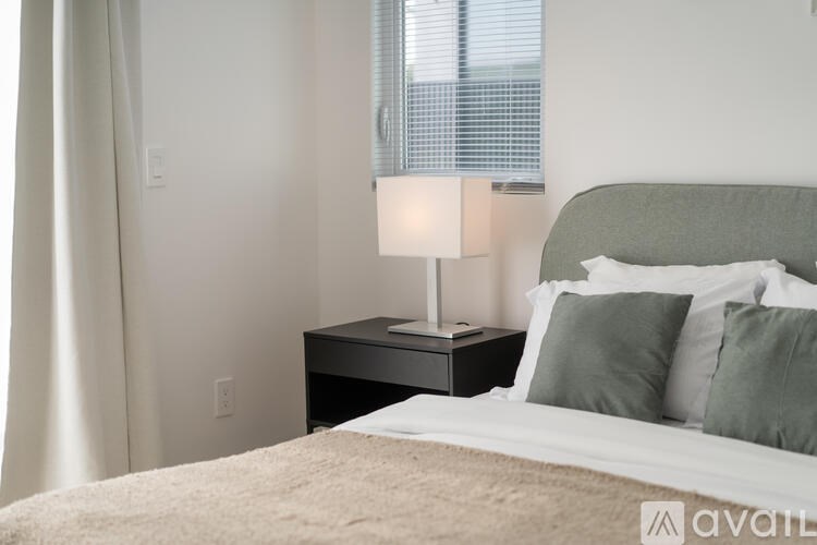 A bedroom with a bed, nightstand, and window.