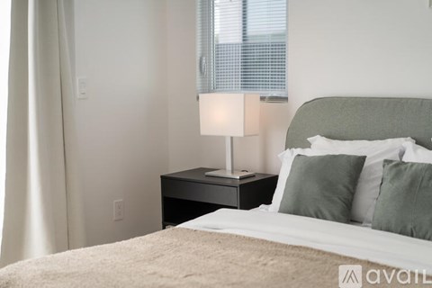 A bedroom with a bed, nightstand, and window.