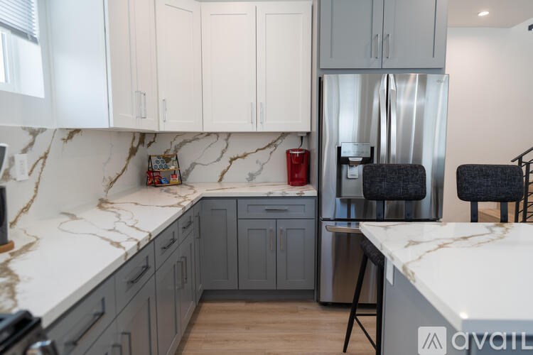 A kitchen with marble countertops and a stainless steel refrigerator.