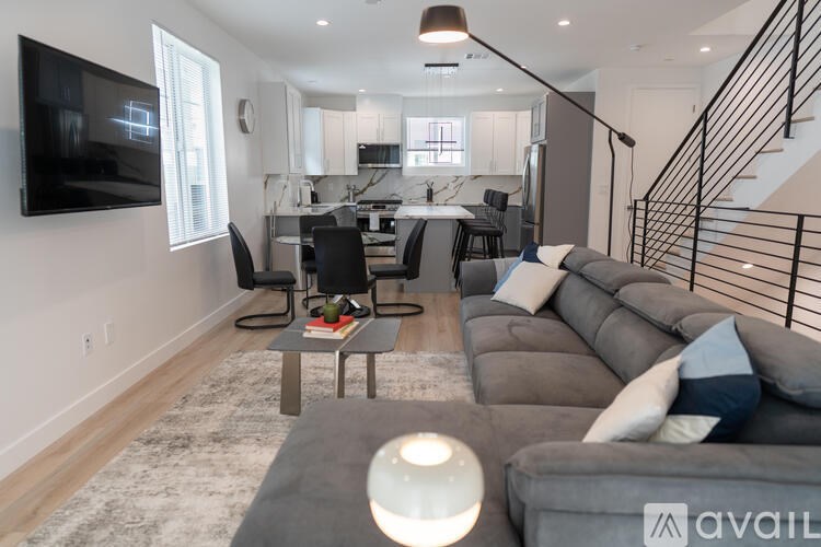 A modern living room with a grey couch and a flat screen TV mounted on the wall.