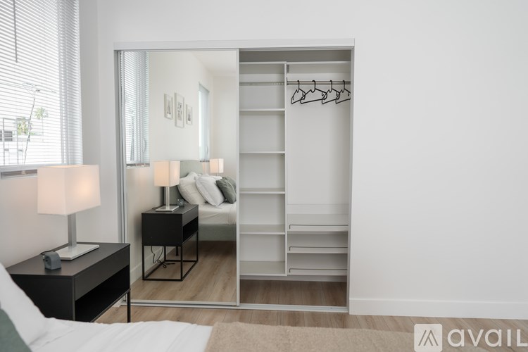 A bedroom with a bed, nightstand, and a mirrored closet.