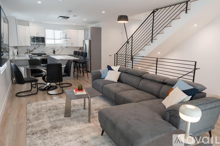 A living room with a grey couch and a black metal staircase.