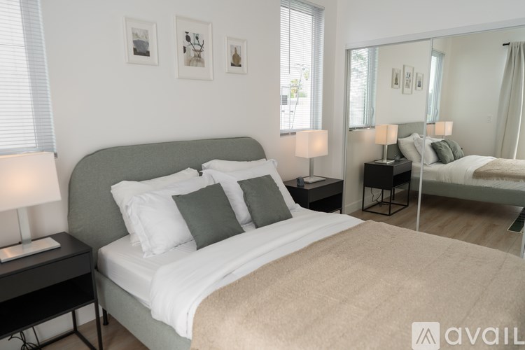 A bedroom with a large bed, a nightstand with a lamp, and a mirror on the wall.