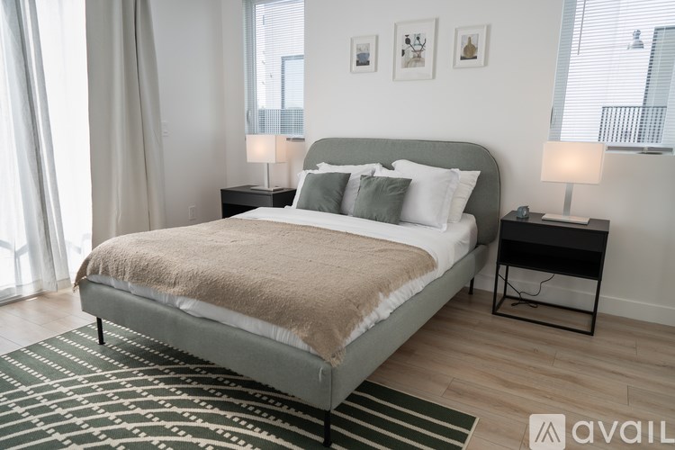 A bedroom with a large bed and a black and white striped rug.