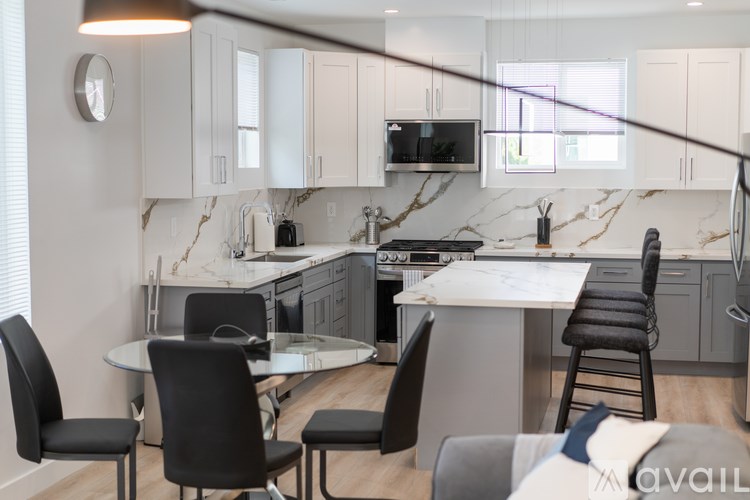 A modern kitchen with a marble backsplash and a dining table set with chairs.