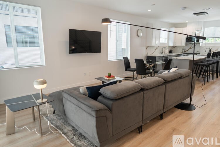 A modern living room with a grey sofa and a flat screen TV mounted on the wall.