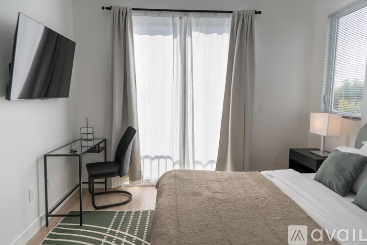 A bedroom with a bed, chair, and a television.