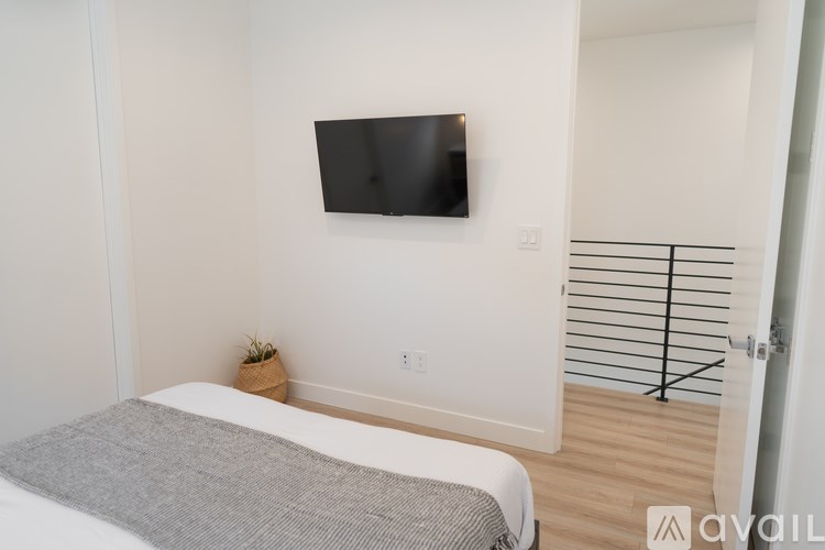 A bedroom with a bed, a small plant, and a flat screen TV mounted on the wall.