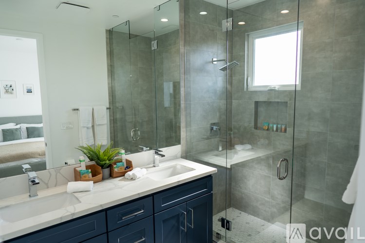 A bathroom with a large mirror, a white sink, and a glass shower stall.