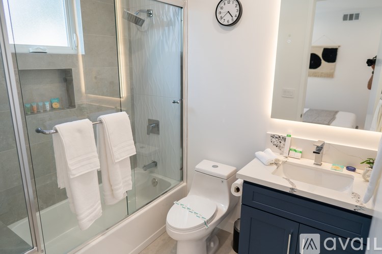 A bathroom with a toilet, sink, mirror, and shower.
