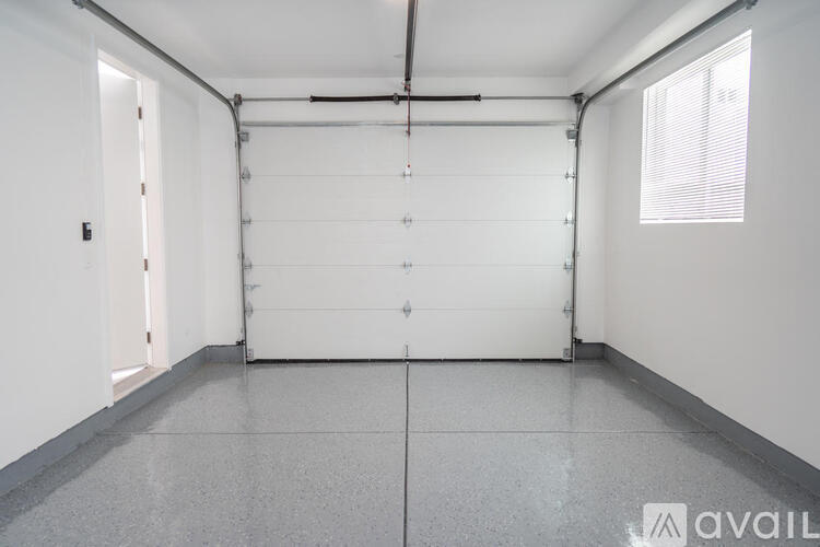 A spacious room with a white door and a window on the right side.
