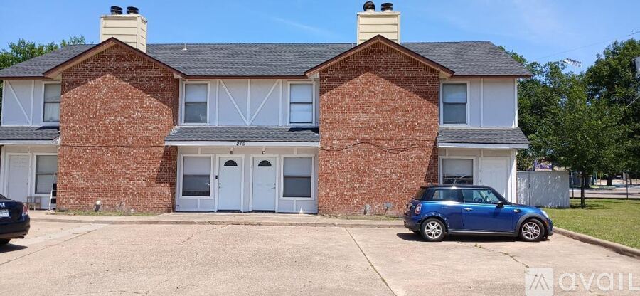 A two-story brick house with a car parked in front.