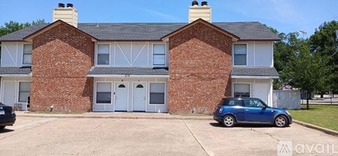 A two-story brick house with a car parked in front.