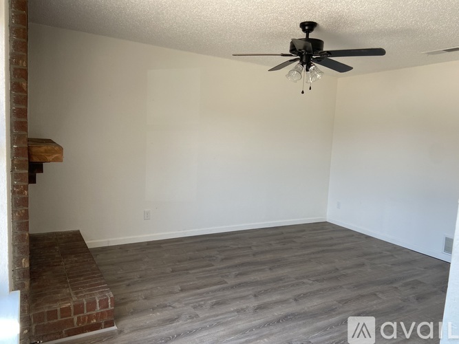 A room with a ceiling fan and wooden flooring.