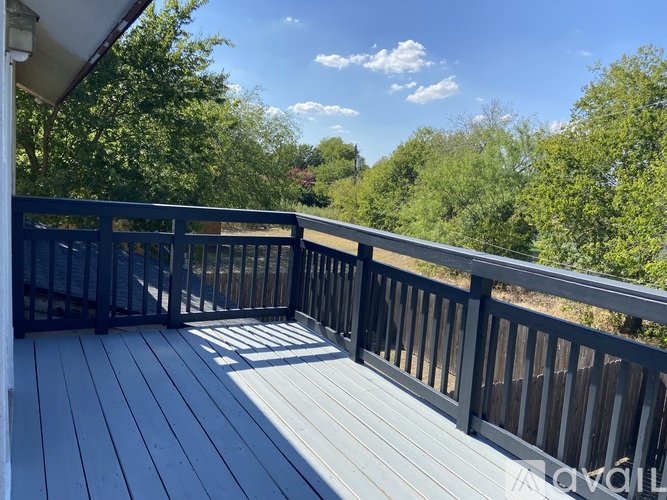 A deck with a railing and trees in the background.