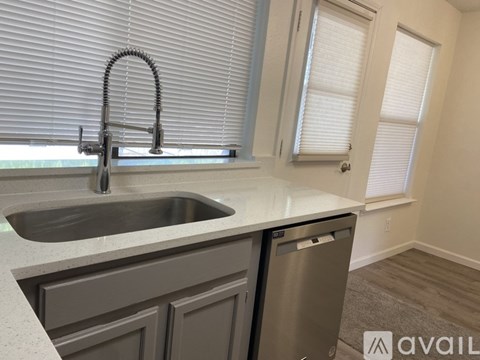 A kitchen with a sink and a window with blinds.