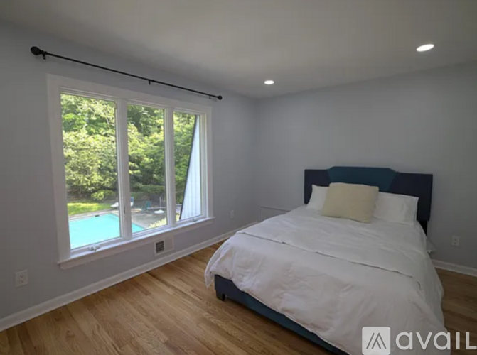 A bedroom with a large bed and a pool outside the window.
