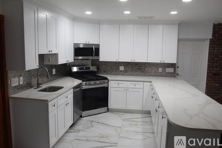 A kitchen with white cabinets and a marble countertop.