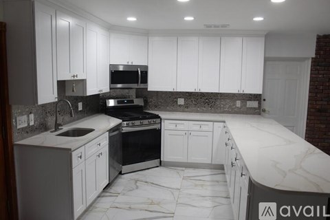 A kitchen with white cabinets and a marble countertop.