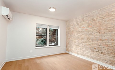 A room with a window and a brick wall.