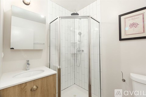 A bathroom with a white sink and a glass shower stall.