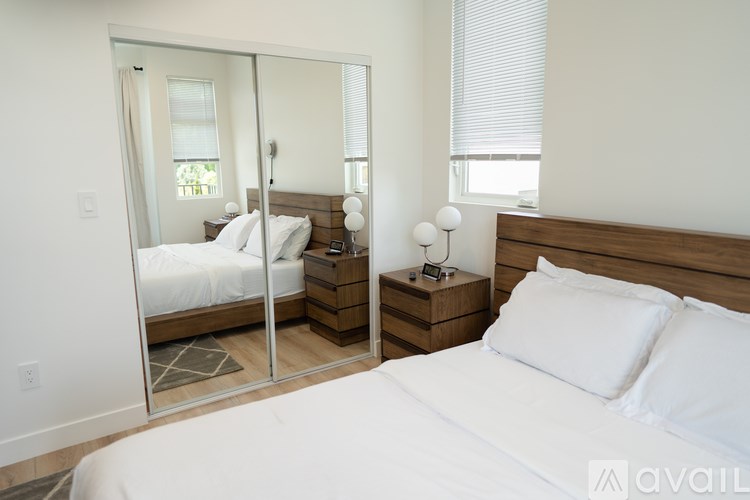 A bedroom with a large bed, a mirror, and a nightstand with a lamp.
