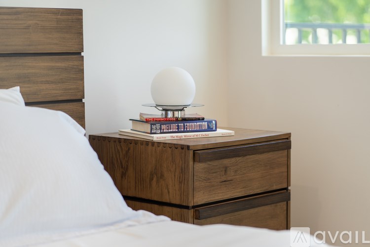 A bedside table with a lamp, books, and a phone on it.