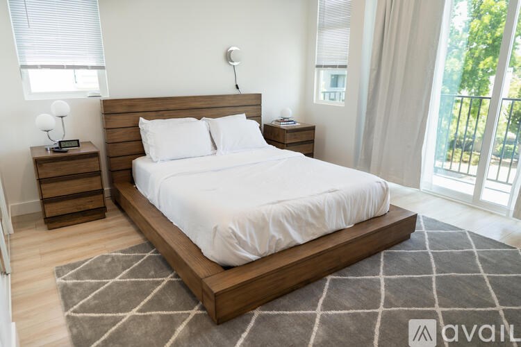 A bedroom with a large bed and a nightstand with a lamp.