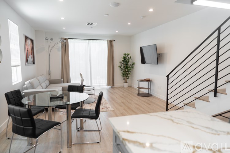 A modern living room with a glass dining table and chairs.