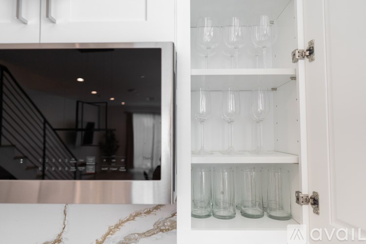 A white cabinet with glasses on the shelf.