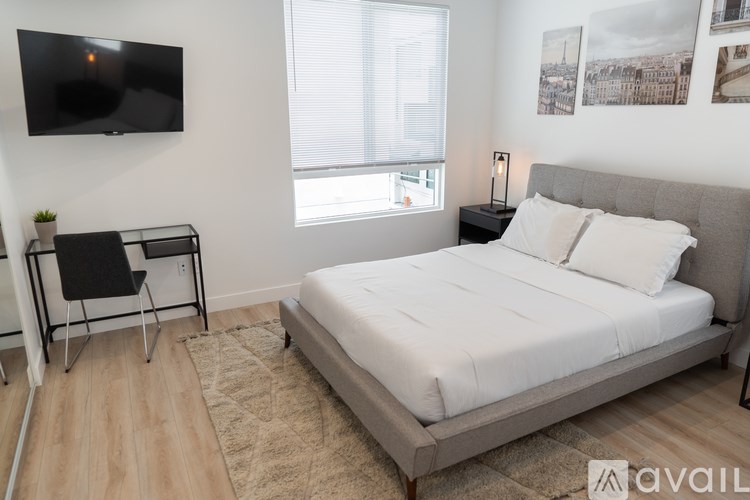 A bedroom with a large bed, a chair, and a television mounted on the wall.