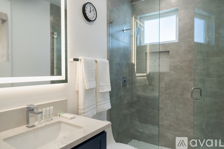 A bathroom with a sink, mirror, and shower.