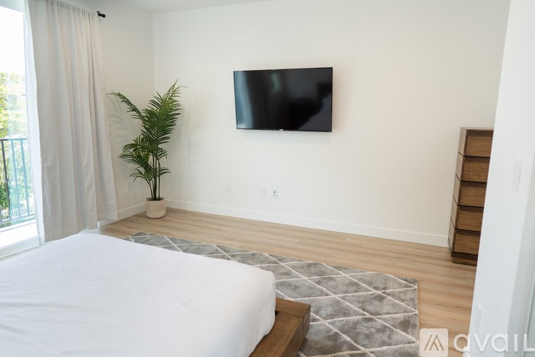 A bedroom with a bed, a TV, and a plant.