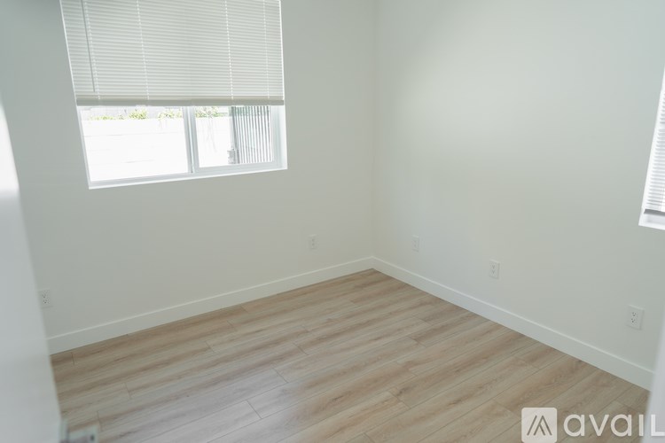 A room with wooden flooring and a window with blinds.
