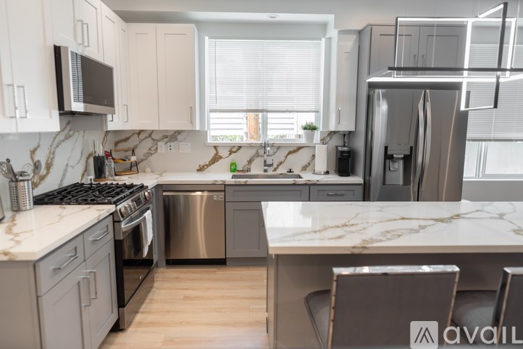 A modern kitchen with a marble countertop and stainless steel appliances.