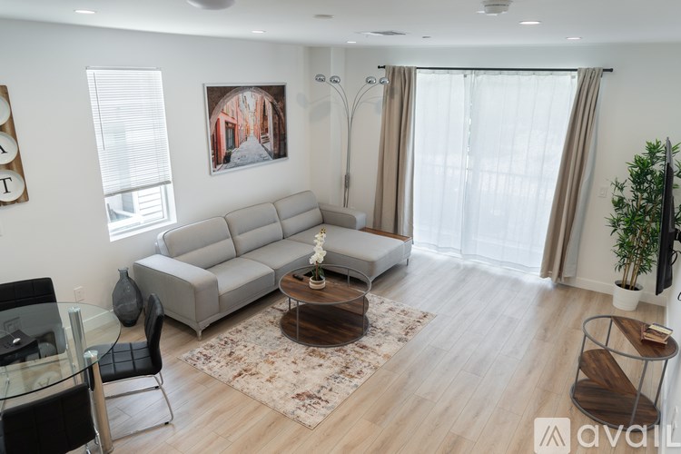 A living room with a glass table and a grey sofa.