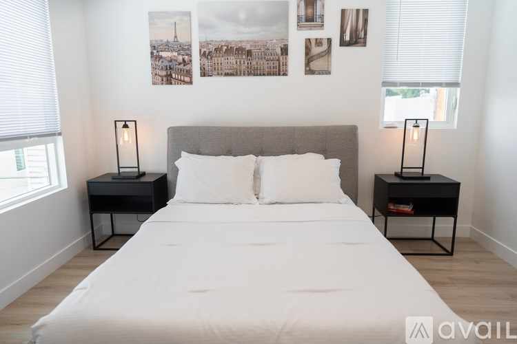 A bedroom with a large bed, two nightstands, and pictures on the wall.