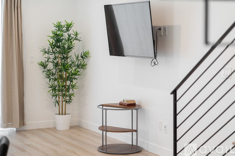 A living room with a TV, a plant, and a small table with a book on it.