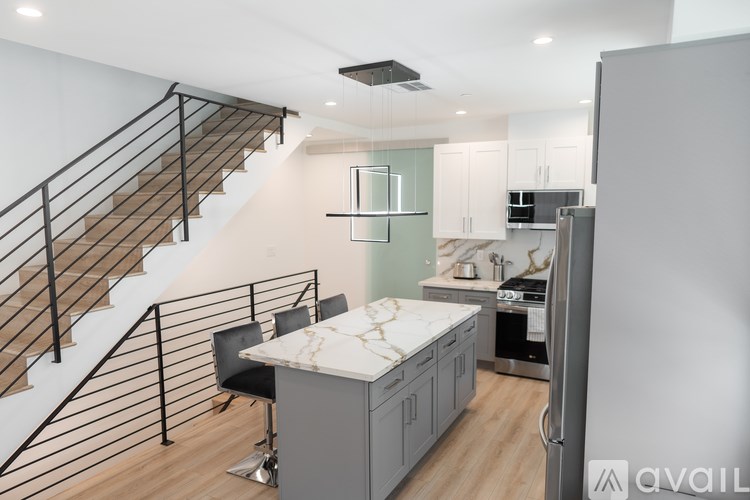 A kitchen with a marble countertop and a staircase with a metal railing.